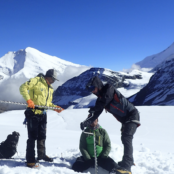 three people installing mass balance stakes in a snowy mountain environment